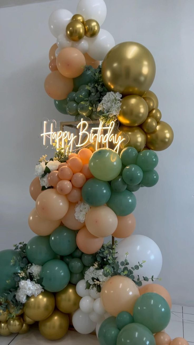 a birthday cake made out of balloons and greenery