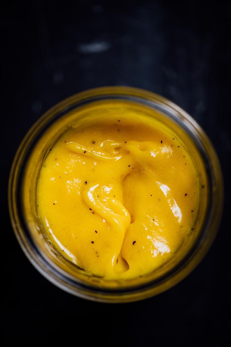 a glass jar filled with yellow sauce on top of a table