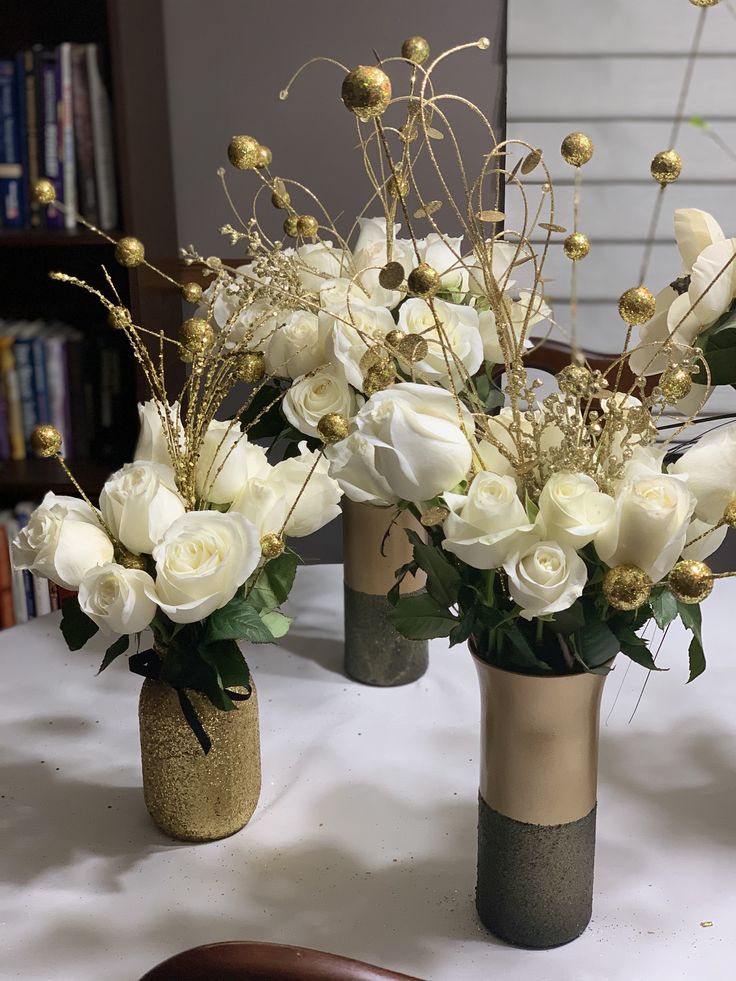 three vases filled with white flowers on top of a table