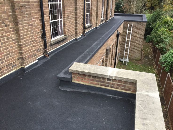 a brick building with a black tarmac and stairs leading up to the top floor