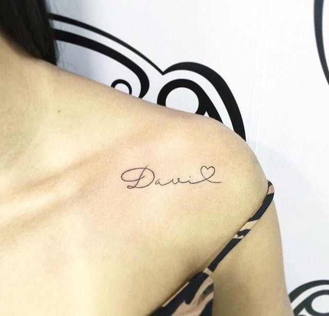 a woman with a small tattoo on her shoulder saying,'love'in cursive font