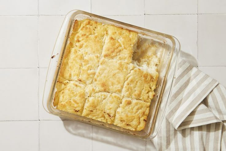 a casserole in a glass dish on top of a striped towel next to a white tiled wall