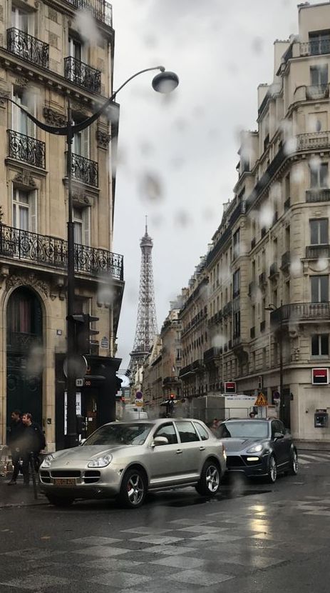 cars are parked on the street in front of tall buildings and eiffel tower