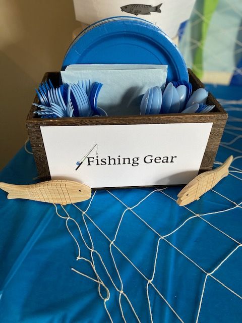 a fishing gear box on a bed with blue sheets and white fish napkins in it