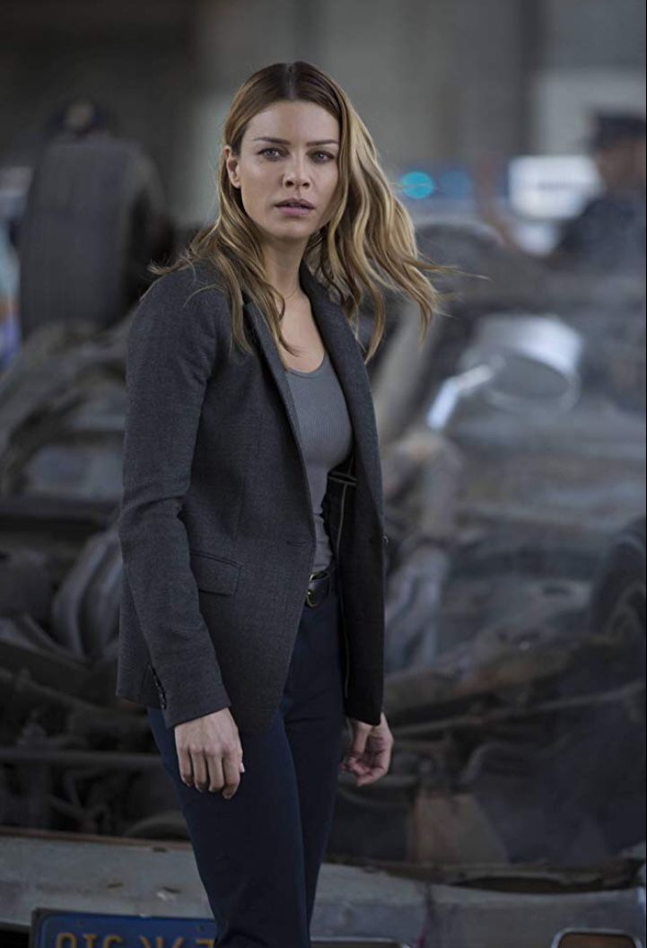 a woman standing in front of a wrecked car