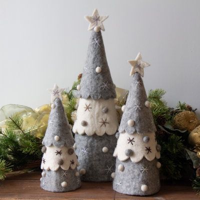 three felt christmas trees sitting on top of a wooden table