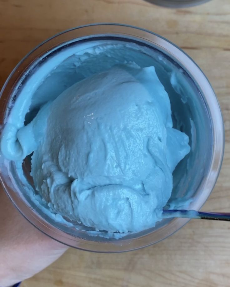 a person holding a spoon in a glass with ice cream