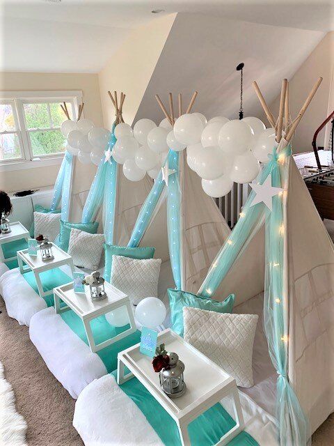 a room filled with lots of white and blue furniture next to a tent covered in balloons