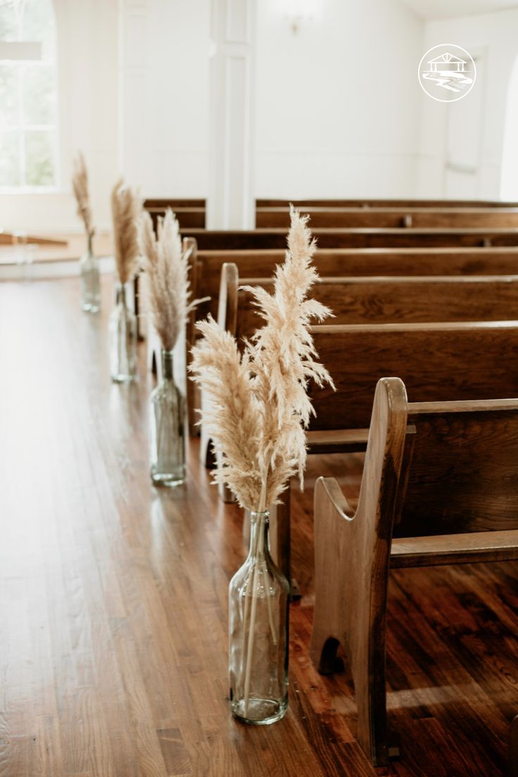 flowers in vases sitting on the pews of a church with empty pews