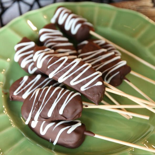 chocolate covered marshmallows sitting on a green plate with toothpicks in them