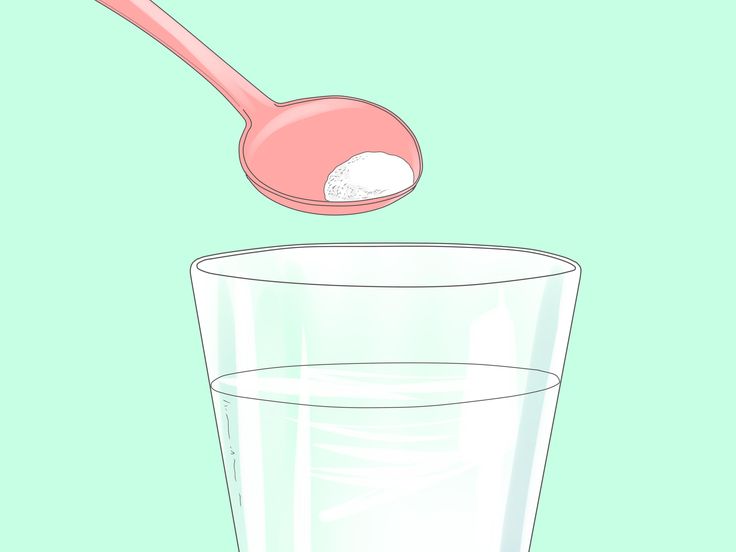 a spoon with sugar in it over a glass of water