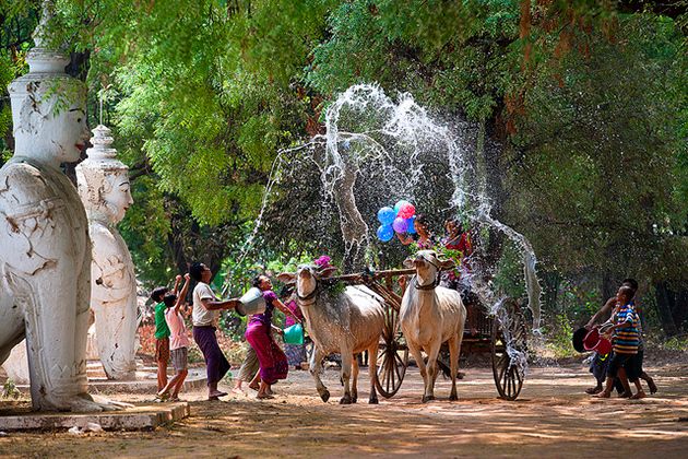 children playing with water from a fountain and donkeys in the foreground, surrounded by statues