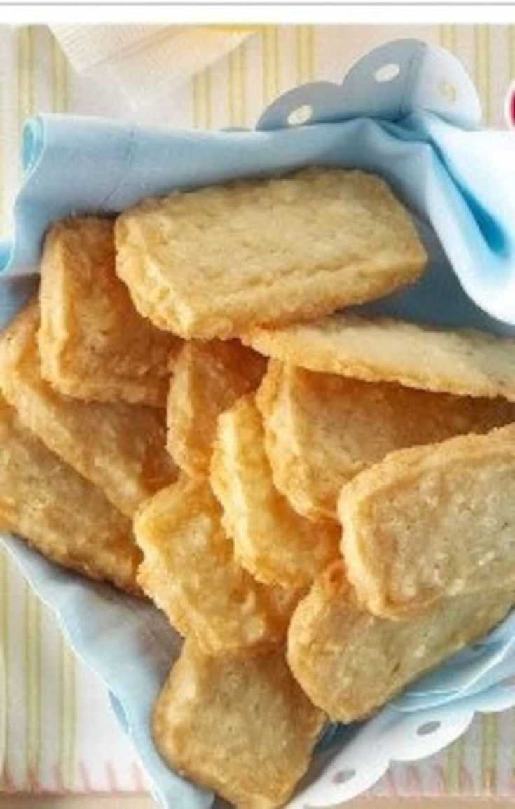 there is a bowl full of crackers on top of a table with a blue cloth