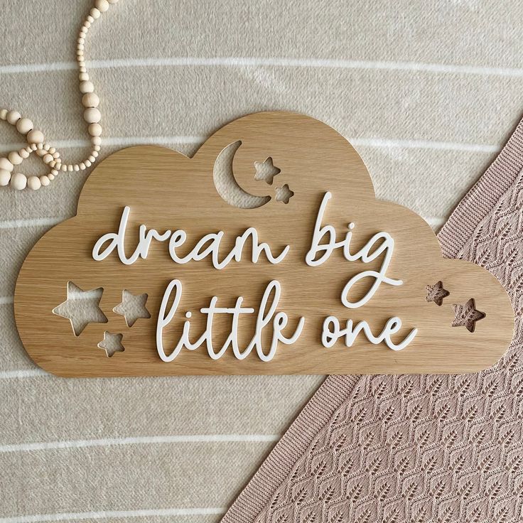 a wooden sign that says dream big little one with stars and the moon on it