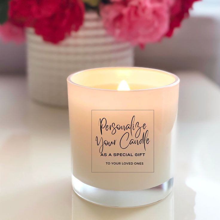 a white candle sitting on top of a table next to some pink and red flowers