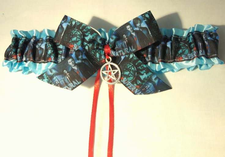 a close up of a bow tie on a white surface with red ribbon and an ornament hanging from it