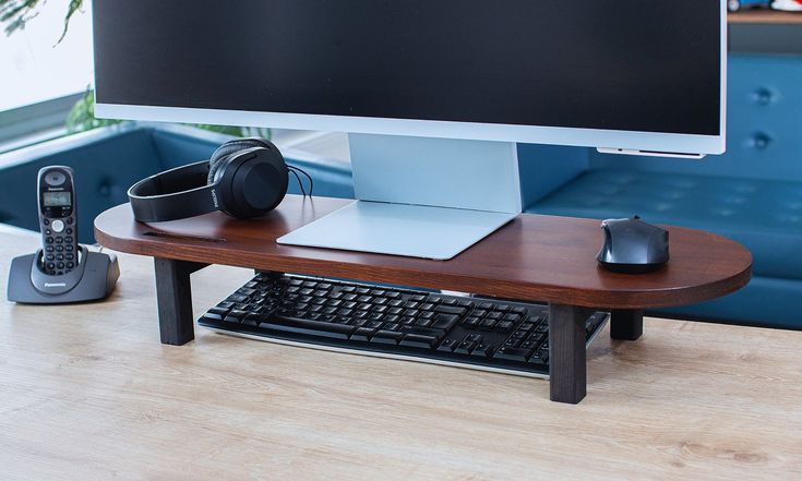 a computer desk with a keyboard, mouse and headphones on it next to a phone