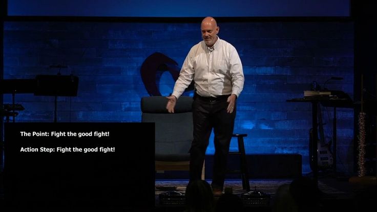 a man standing on stage with his hands in his pockets and looking at the ground