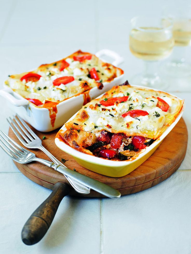 two casseroles on a wooden platter with silverware