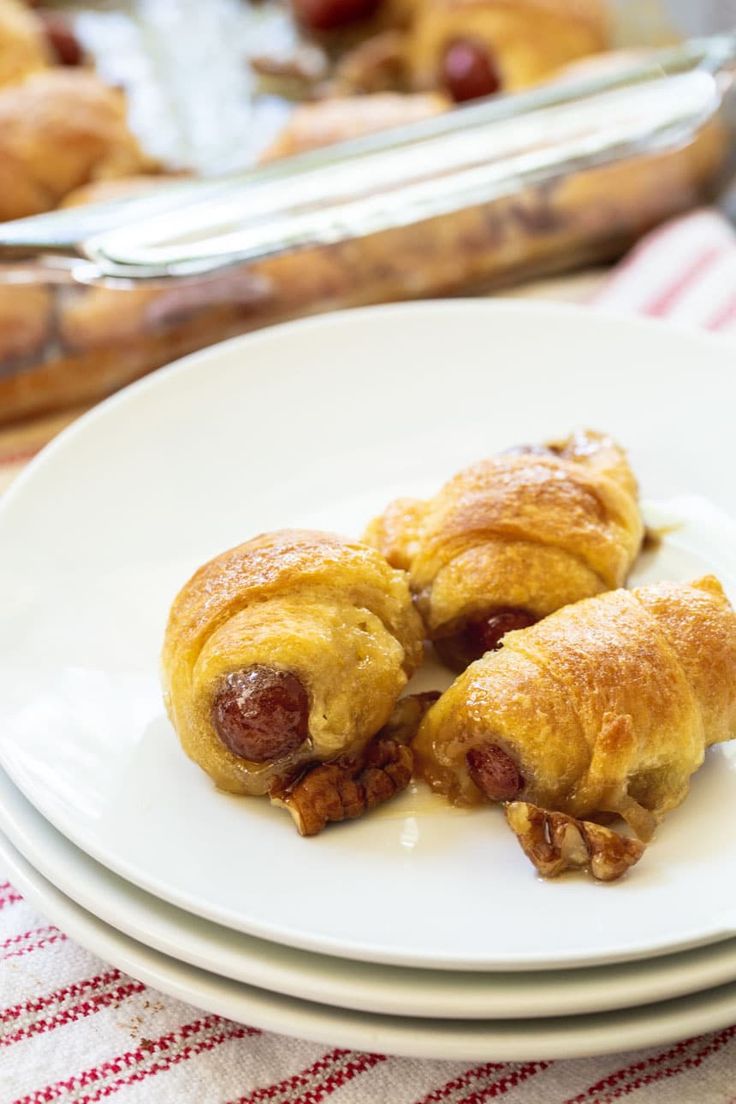 two croissants sitting on top of white plates next to a casserole dish