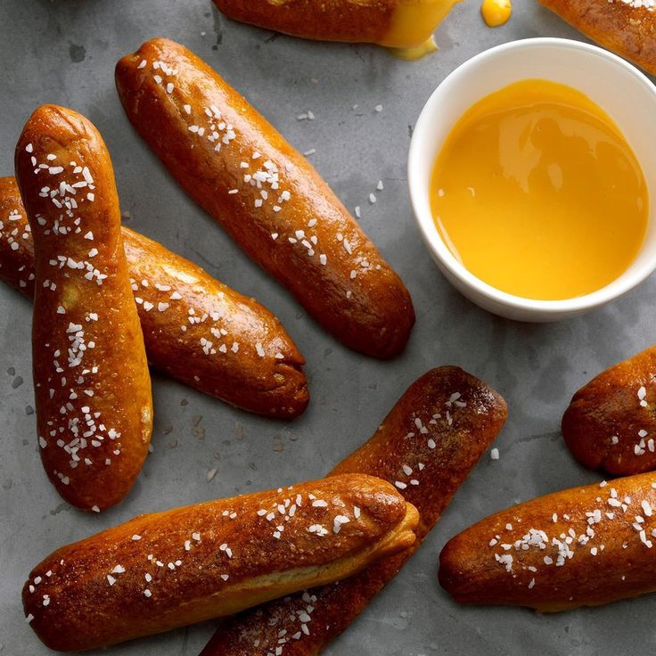 breadsticks are arranged on a table with mustard in a small bowl next to them