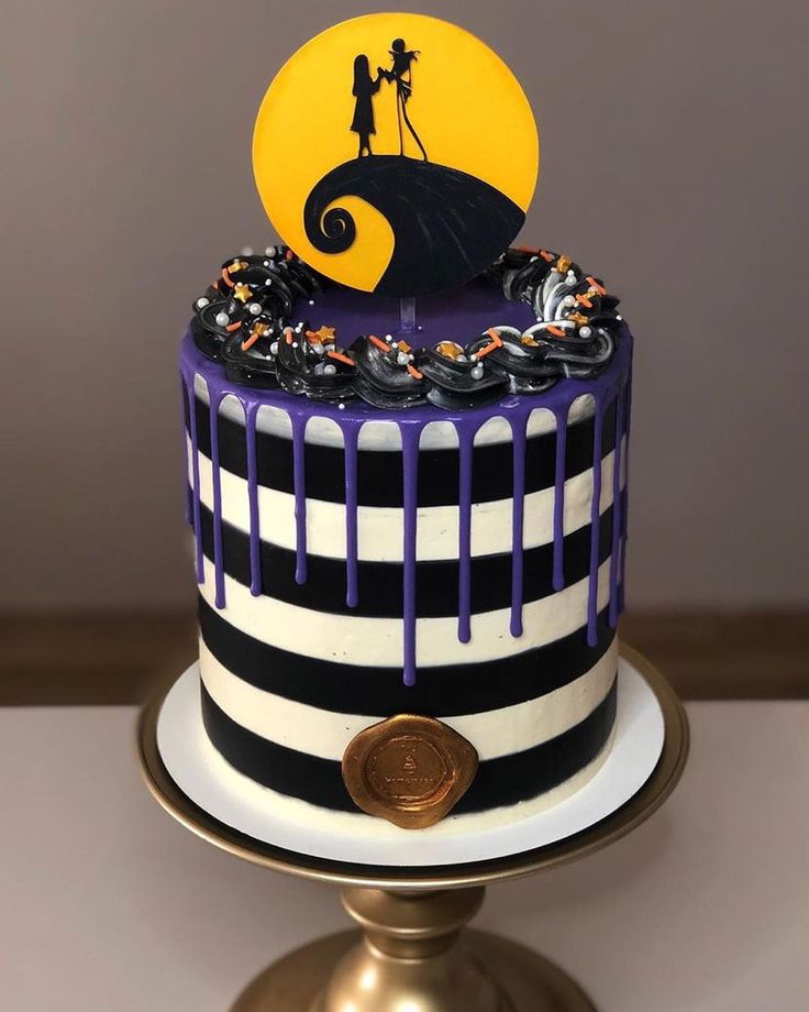 a halloween cake decorated with black, white and purple icing on a gold plate