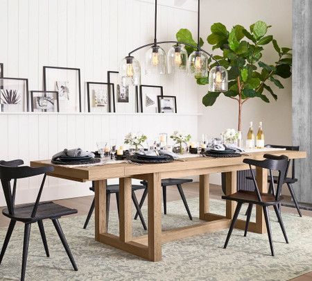 a dining room table with chairs and pictures on the wall in the backround