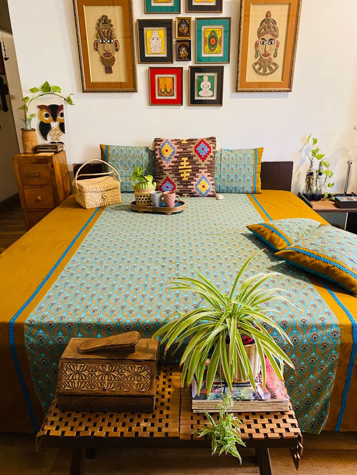 a bed with blue and yellow bedspread in front of pictures on the wall