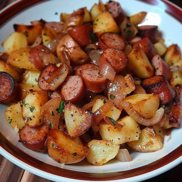 a white plate topped with cooked potatoes and sausages on top of a wooden table