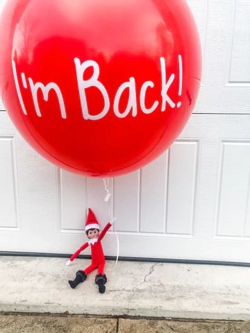 a red balloon with the words i'm back written on it and an elf holding a string