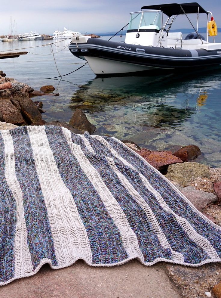 a boat is docked in the water next to a beach towel on rocks with a blue and white stripe