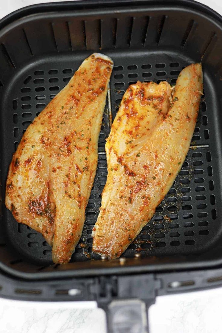 two pieces of chicken cooking in an air fryer