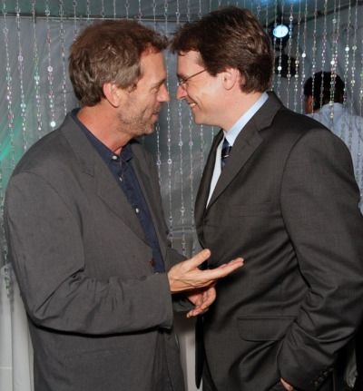 two men standing next to each other in front of a wall covered with sequins