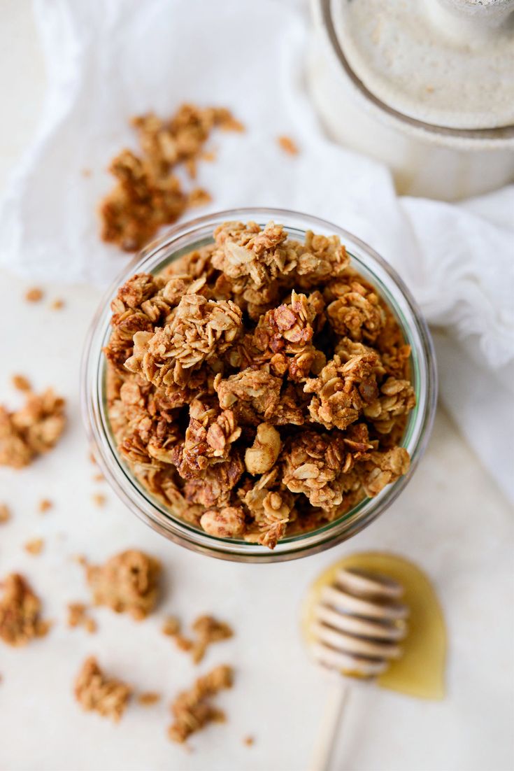 a glass bowl filled with granola next to a jar of honey