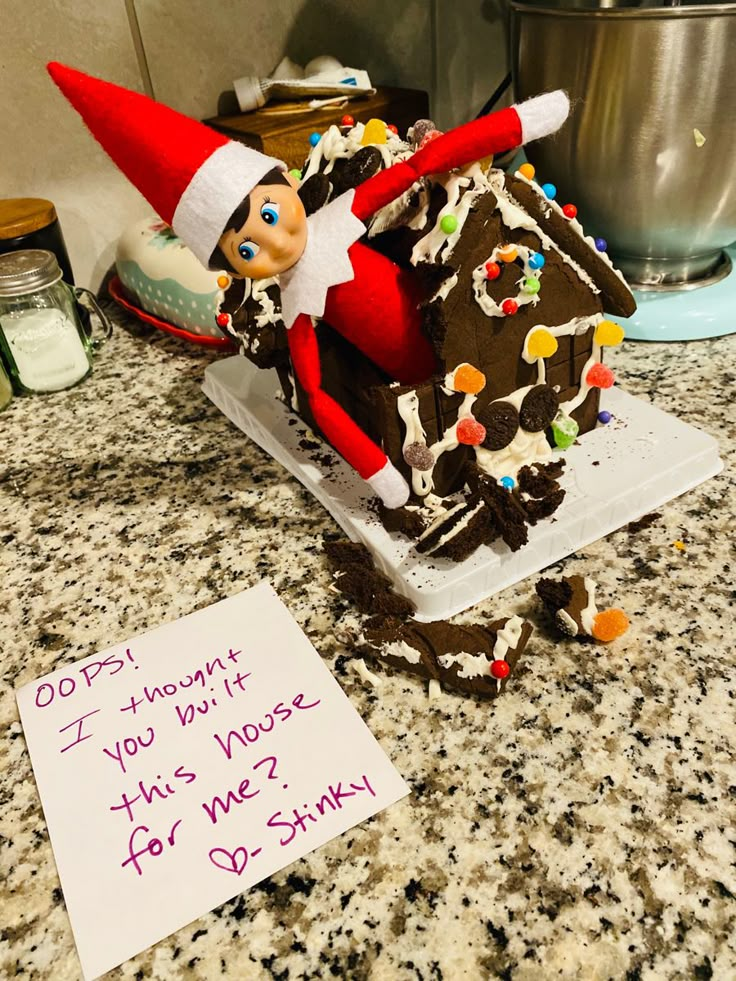 an elf is sitting on top of a gingerbread house