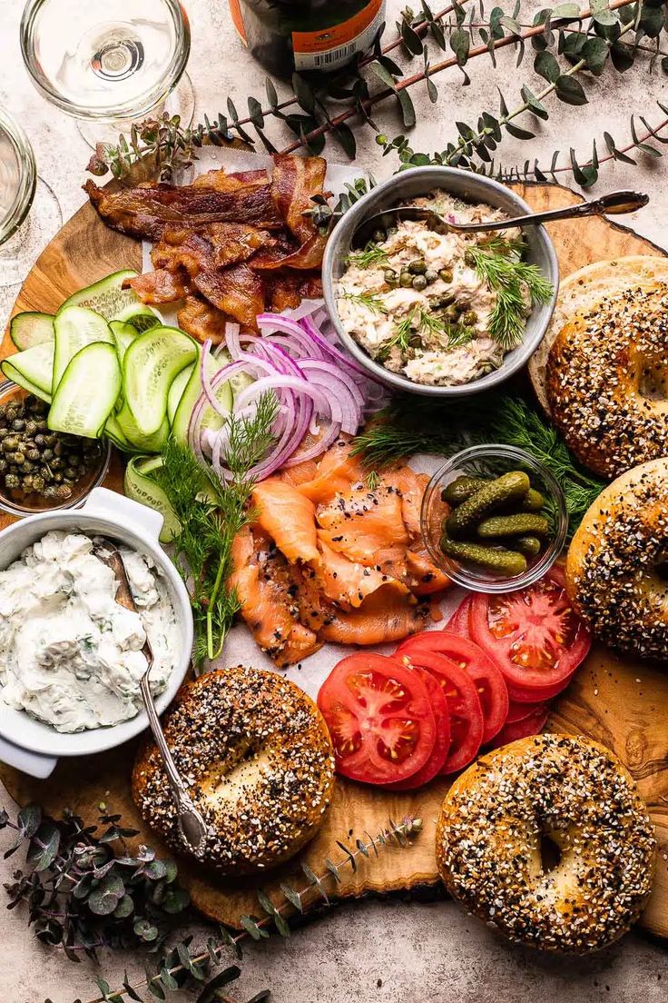 an assortment of bagels and vegetables on a cutting board