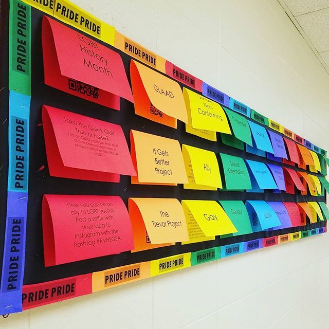 a bulletin board with post it notes attached to the back wall in a school hallway