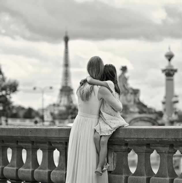 two women hugging each other on a bridge in front of the eiffel tower