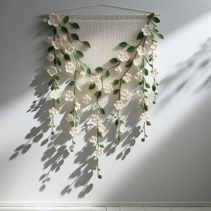 a wall hanging with white flowers and green leaves