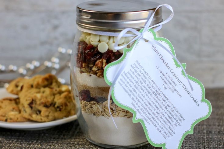 a cookie in a jar next to a white plate with cookies on it and a paper tag