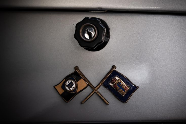 two flags and a button on the back of a car's hood ornament