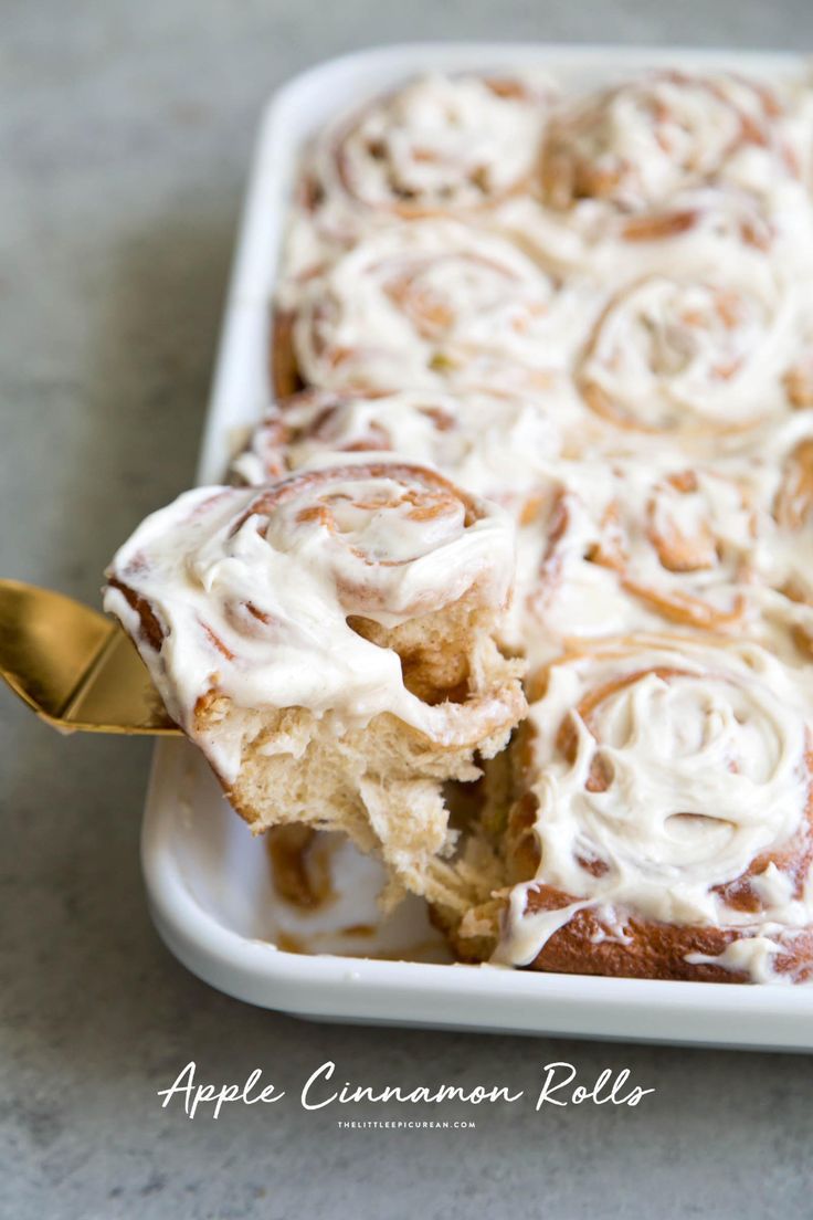 an apple cinnamon roll with icing in a white dish