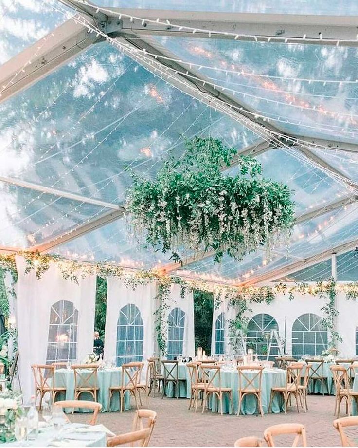 the inside of a tent with tables, chairs and chandelier hanging from the ceiling