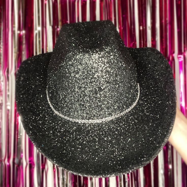 Black Glitter with Rhinestone Band Cowboy Hat. This cowboy hat is the perfect addition to your party, events, and even cute photos! This is an adult-sized, polyester cowboy hat sealed in glitter with a single rhinestone band. The glitter is only on the top of the hat ensuring that it will not get in your hair! The bottom of the hat is black matching the glitter color. The hat circumference is 23 inches. Keep in mind that this is not a fitted cowboy hat, one size fits most but it ranges on the la Black Sparkly Cowboy Hat, Black Glitter Cowboy Hat, Black Rhinestone Cowboy Hat, Western Style Party Top Hat With Curved Brim, Western Style Top Hat With Curved Brim For Party, Western Style Curved Brim Top Hat For Party, Western Curved Brim Costume Hat For Parties, Western Fedora Party Hat, Western Fedora Hat For Party