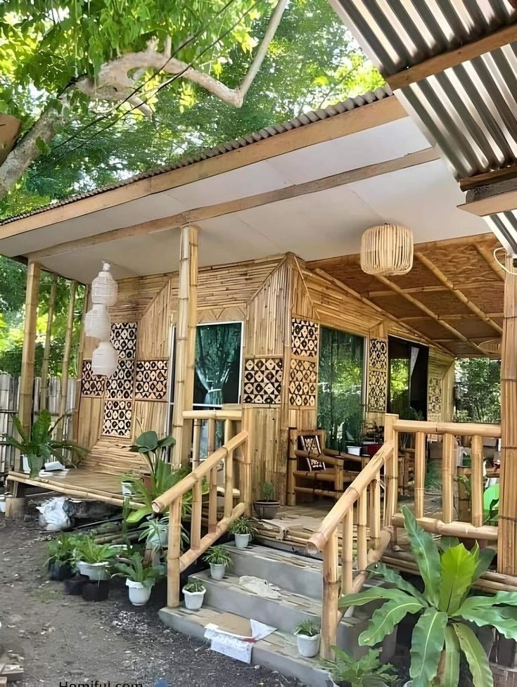 a bamboo house with steps leading to the front door and covered porch area, surrounded by greenery