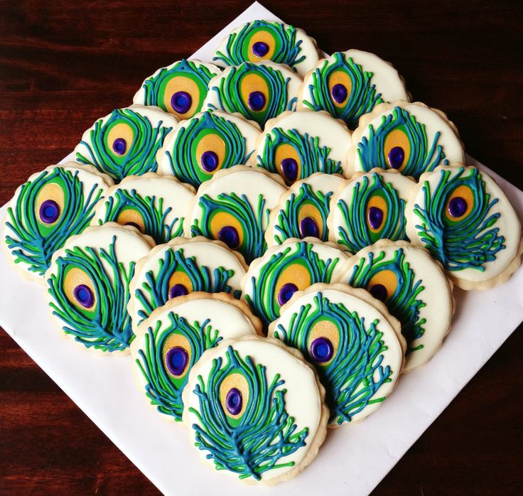 peacock decorated cookies are arranged on a white plate