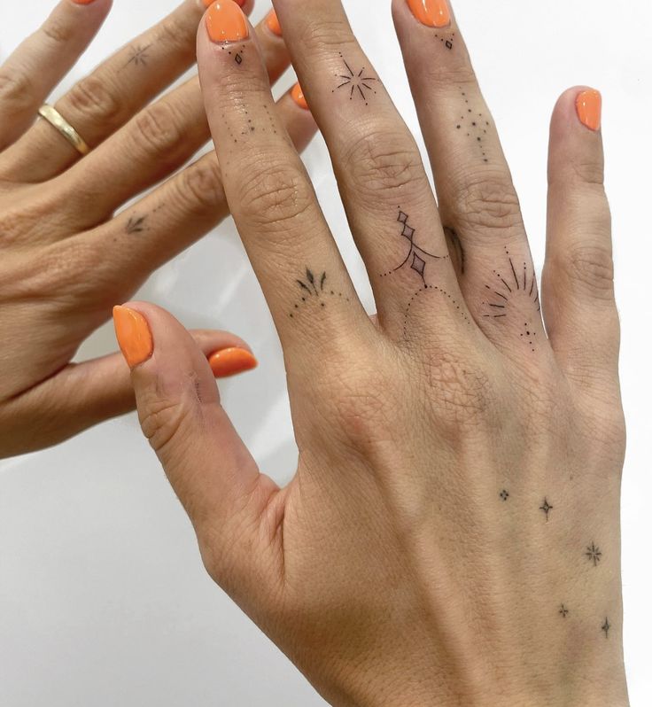 two hands with tattoos on their fingers and one has an orange manicured nail polish