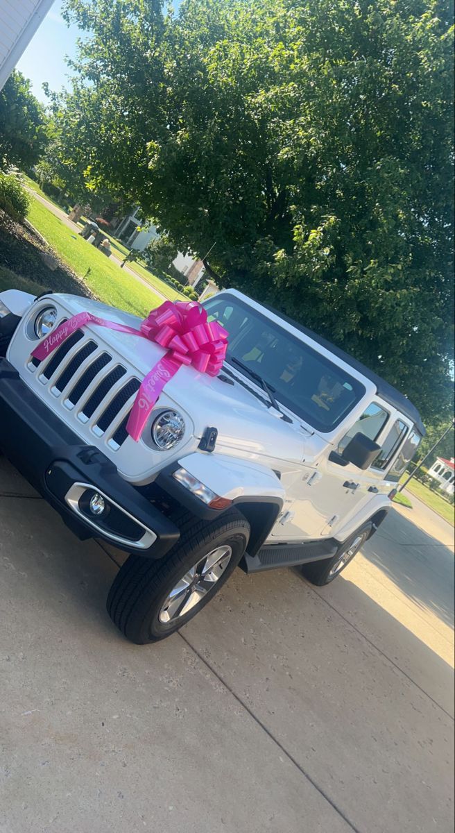 a white jeep with a pink ribbon tied to it