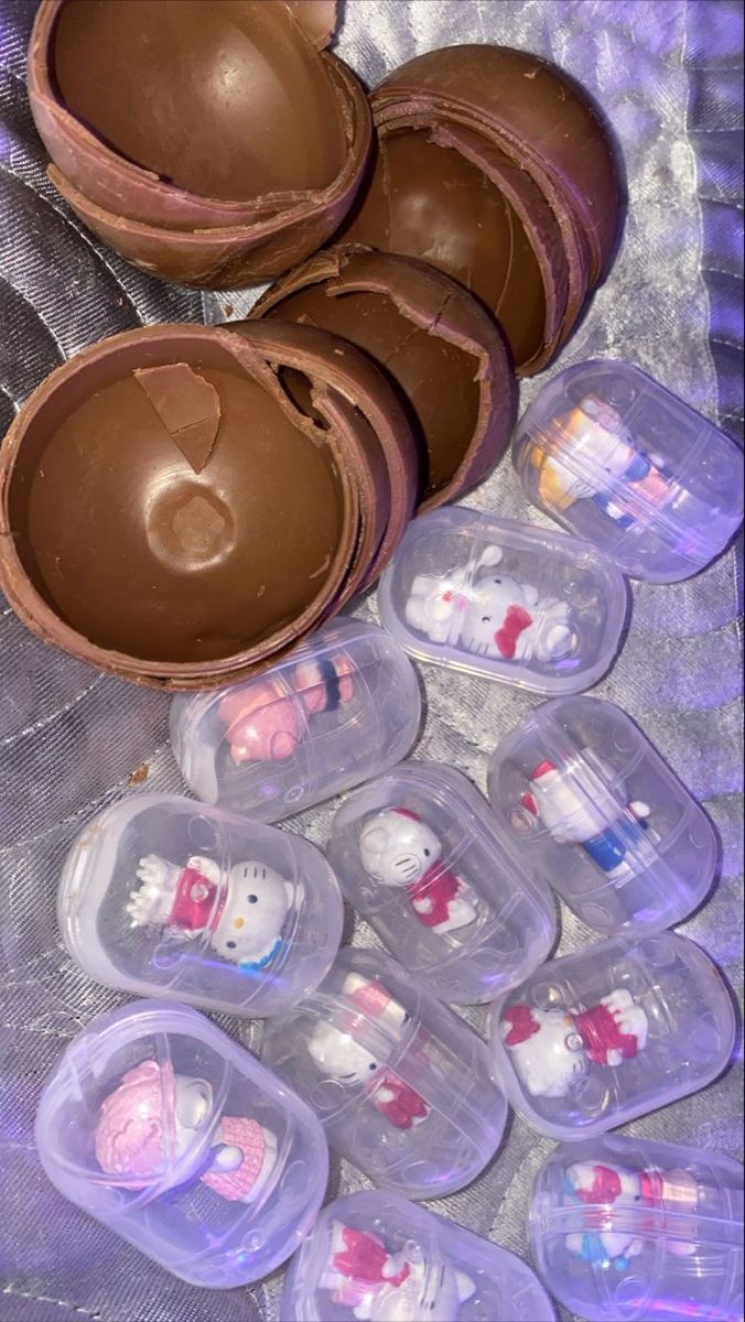 several plastic containers filled with chocolate covered hello kitty candies on a silver tablecloth