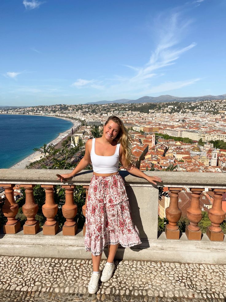 a woman standing on top of a balcony next to the ocean